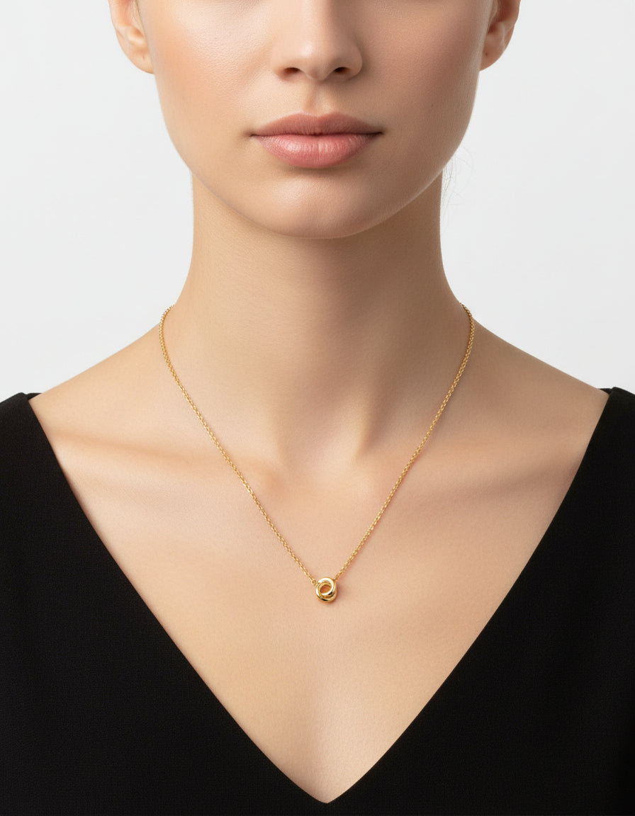 Gold necklace with a circular pendant on a light gray background